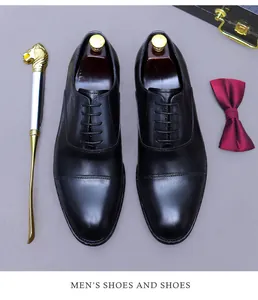 Vista superior de zapatos oxford de cuero negro con hormas, calzador y pajarita roja