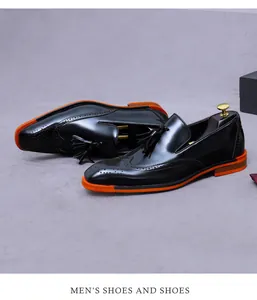 Dettaglio scarpe brogue in pelle verniciata nera con frange e suola arancione alla moda
