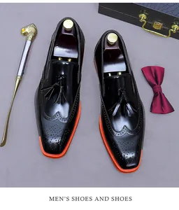 Dettaglio di scarpe brogue in pelle verniciata nera con nappa e suola arancione