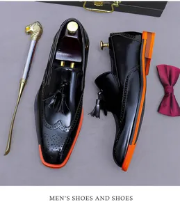 Dettaglio macro di scarpe brogue in vernice nera con nappe e suole arancioni a contrasto