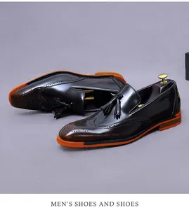 Dettaglio di mocassini con nappe in pelle marrone con brogue e suola arancione