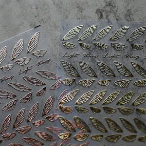 Pegatinas para uñas en oro y oro rosa con alas de insecto y texto caligráfico elegante