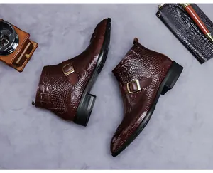 Gros plan de bottines en cuir marron à motif crocodile avec boucle en laiton