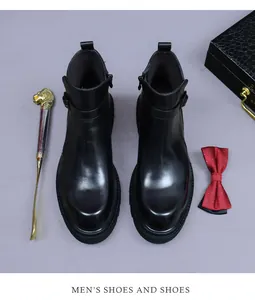 Gros plan de bottines Chelsea en cuir noir avec fermeture éclair et accessoires chic