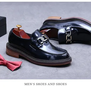 Detail of glossy black leather loafer with metal chain link and thick sole