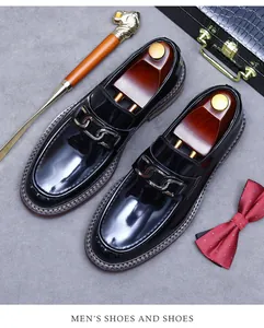 Close-up of black patent leather loafers with silver chain and classic business accessories