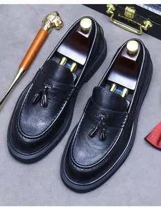 Détail de mocassins à glands en cuir noir grainé avec des accessoires de gentleman