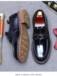 Detailed top view of black patent leather loafers with metal chain and classic props