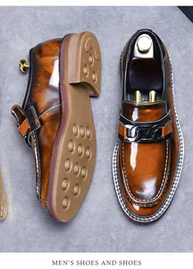 Detail view of brown leather loafers with metal chain buckle and non-slip rubber soles