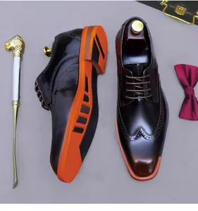 Detailed top view of men's dark brown brogue shoes with vibrant orange rubber soles