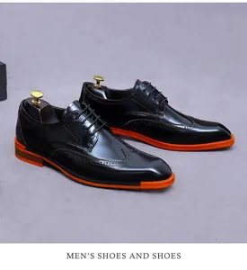 Detail of men's black brogue leather shoes featuring orange rubber soles and carvings