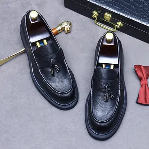 Mocassins à gland en cuir noir avec semelle épaisse et embauchoirs sur fond sombre élégant