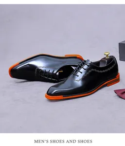 Détail de chaussures oxford en cuir verni noir avec semelles orange et accents dorés