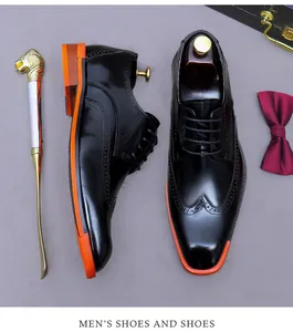 Flat lay of men's black leather wingtip brogues with vibrant orange soles and accessories