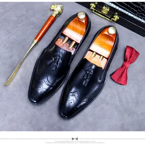 Detail of black leather loafers with tassel and brogue design beside elegant accessories