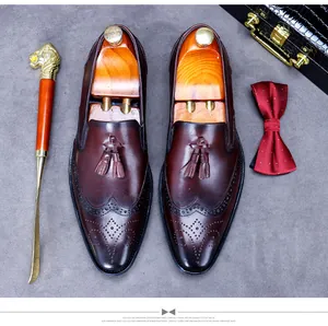 Macro detail of dark brown leather tassel loafers with brogue wingtip patterns and shoe horn