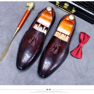 Flat lay of brown leather tassel loafers with brogue details and elegant accessories