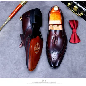 Top-down view of men's leather tassel loafers with wingtip brogue details and suit accessories