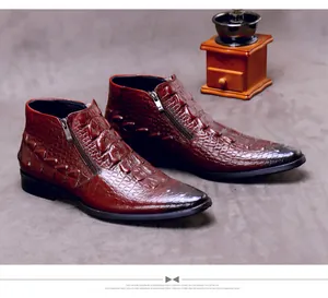 Primer plano de botas de hombre en cuero marrón rojizo con grabado de cocodrilo y cremallera