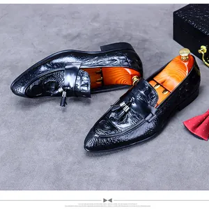 Detail of black leather loafers featuring embossed crocodile texture and decorative tassels