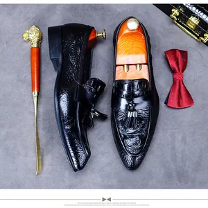 Detail view of crocodile-embossed leather loafers with double tassels and business props