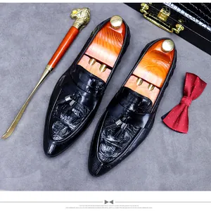Luxury black leather loafers with crocodile pattern and tassels on a premium background