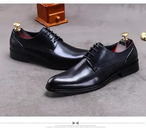 Nahaufnahme schwarzer Derby-Schuhe aus Leder mit Brogue-Lochmustern und gewachsten Schnürsenkeln