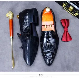 Detail of black crocodile embossed leather loafers with decorative tassels and luxury accessories