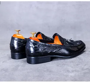 Detail of black crocodile embossed leather loafers with classic tassel and moccasin stitching