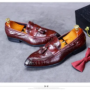 Macro detail of brown crocodile embossed leather loafers with decorative tassels and accessories