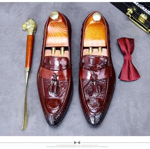 Close-up of brown leather loafers with crocodile texture, tassels, and business accessories