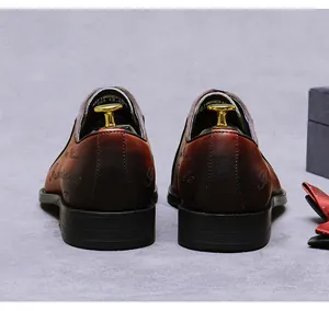 Detalle de zapatos Oxford de cuero marrón degradado con letras decorativas y horma dorada
