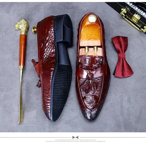 Detail view of brown crocodile pattern leather tassel loafers with a decorative shoe horn