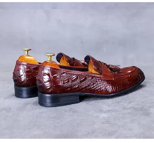 Detail of reddish-brown leather loafers with crocodile embossing and tassel decoration