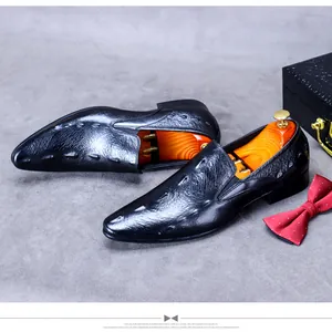 Details von schwarzen Leder-Business-Schuhen mit Prägung und einer roten Fliege