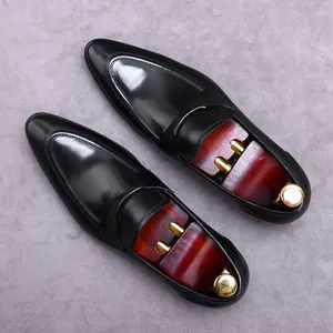Polished black leather loafers for men with premium wooden shoe trees on a grey background