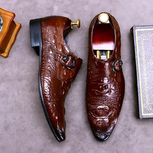 Brown crocodile embossed leather monk strap shoes with metallic buckles and wooden shoe trees