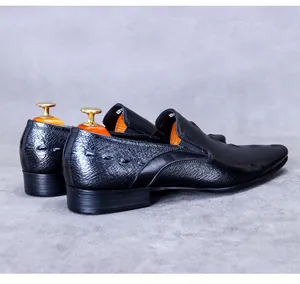 Detailansicht der schwarzen Kroko-Leder-Schuhe mit Ziernaht und hölzernem Schuhspanner