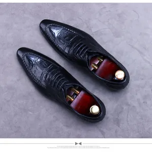 Detailed top view of black leather dress shoes with crocodile texture and woven edges