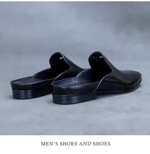 Detail view of smooth black leather mules for men with side embossed text and flat sole