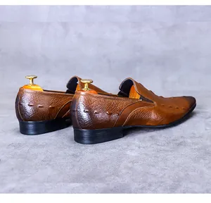 Detail von braunen Leder-Loafers mit Krokoprägung und hölzernem Schuhspanner im Inneren