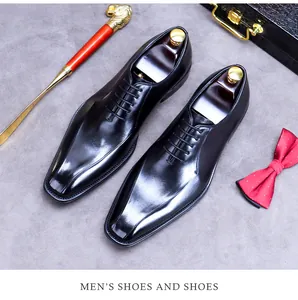Polished black leather men's dress shoes with wooden shoe trees on grey background
