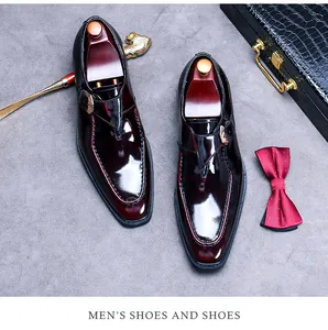 Polished burgundy monk strap shoes with buckle and wooden shoe trees on grey background