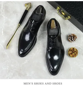 Polished black leather Derby shoes for men with wooden shoe trees on marble background