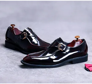 Detail of high-gloss burgundy monk strap shoe with gold buckle and a red polka dot bowtie