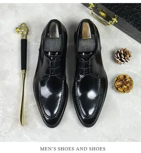 Detailed top view of black leather derby shoes with U-tip stitching on marble background