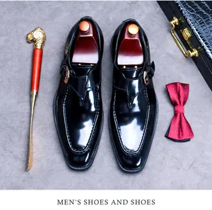 Polished black leather monk strap shoe with gold buckle detail and wooden shoe tree