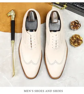 Detailed brogue perforation on premium off-white leather dress shoes with wooden shoe tree