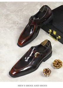 Close-up of polished dark brown monk strap leather shoes with a gold buckle on marble