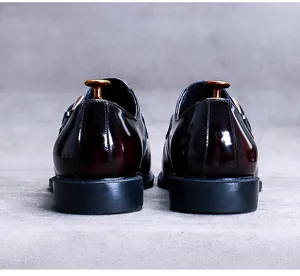 Rear view of glossy burgundy leather monk strap shoes with polished finish and metal buckles